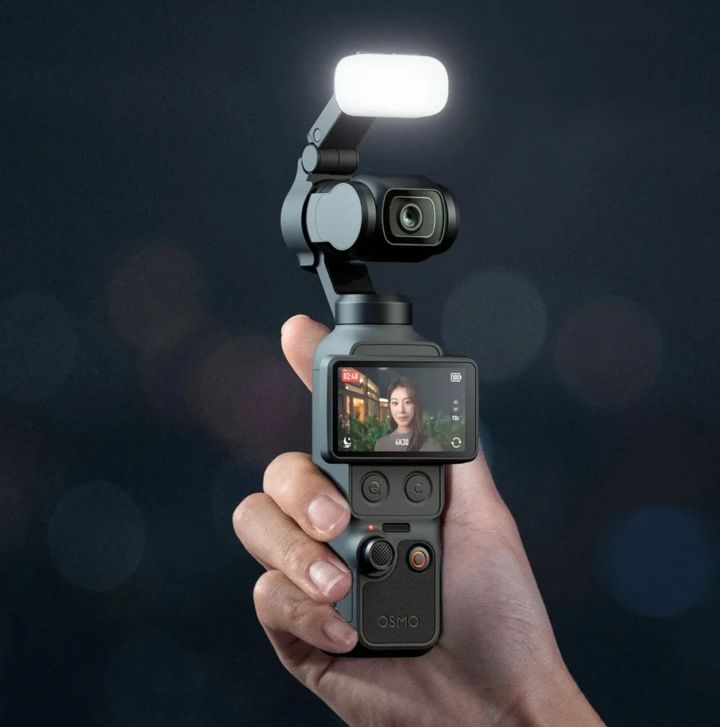 Камера DJI Osmo Pocket 4 с установленным магнитным заполняющим светом в руке оператора в темной студии